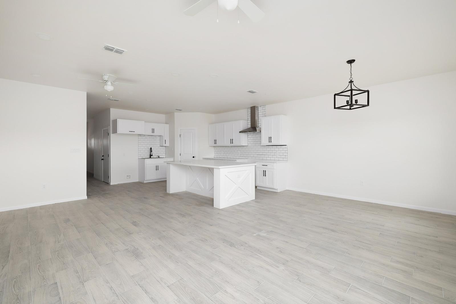 2015 Cassandra · open kitchen and living looking through to dining with lantern pendant and white finishes