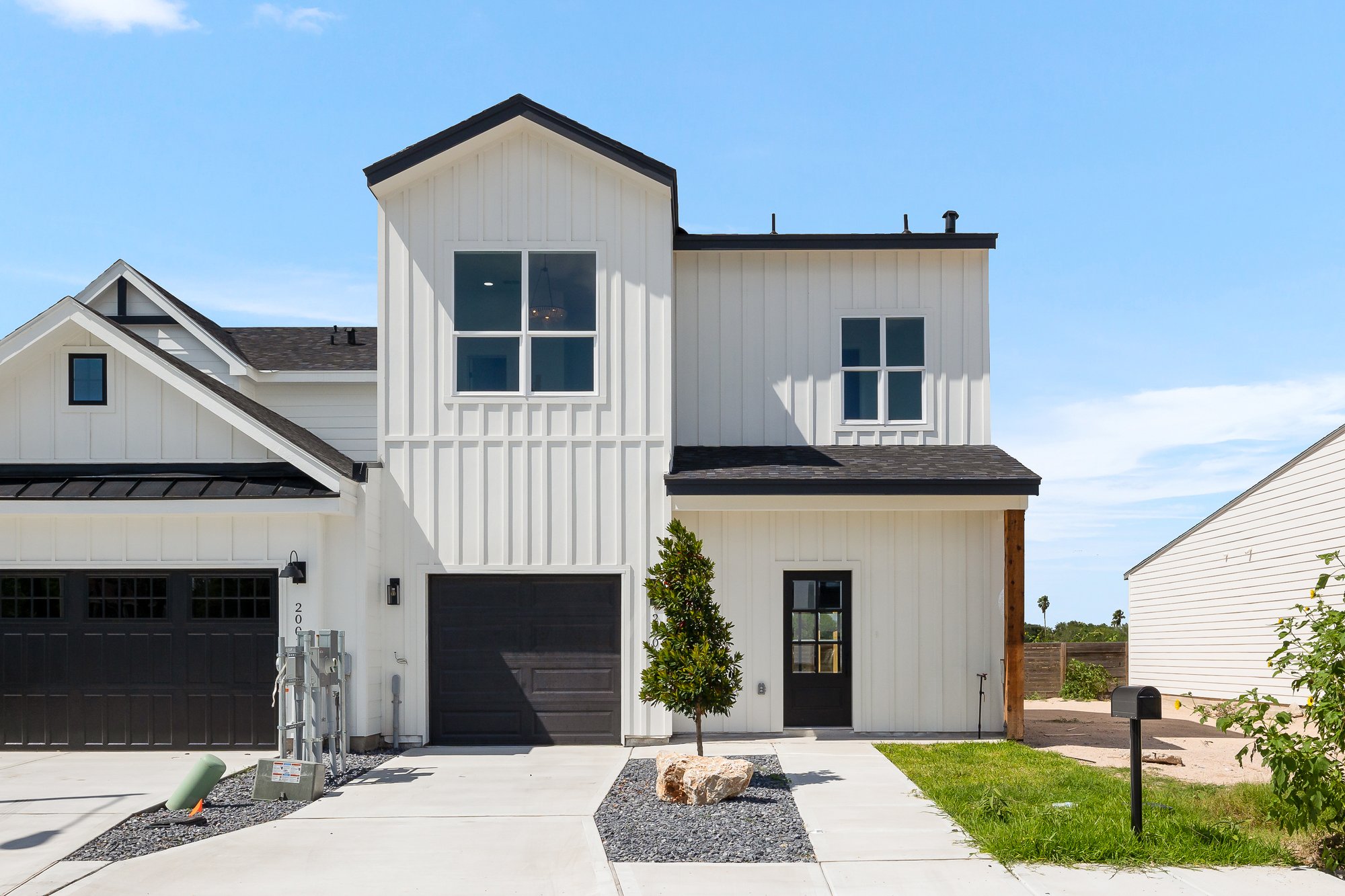 2003 Cassandra · smaller two storey modern farmhouse with white board and batten facade and black garage