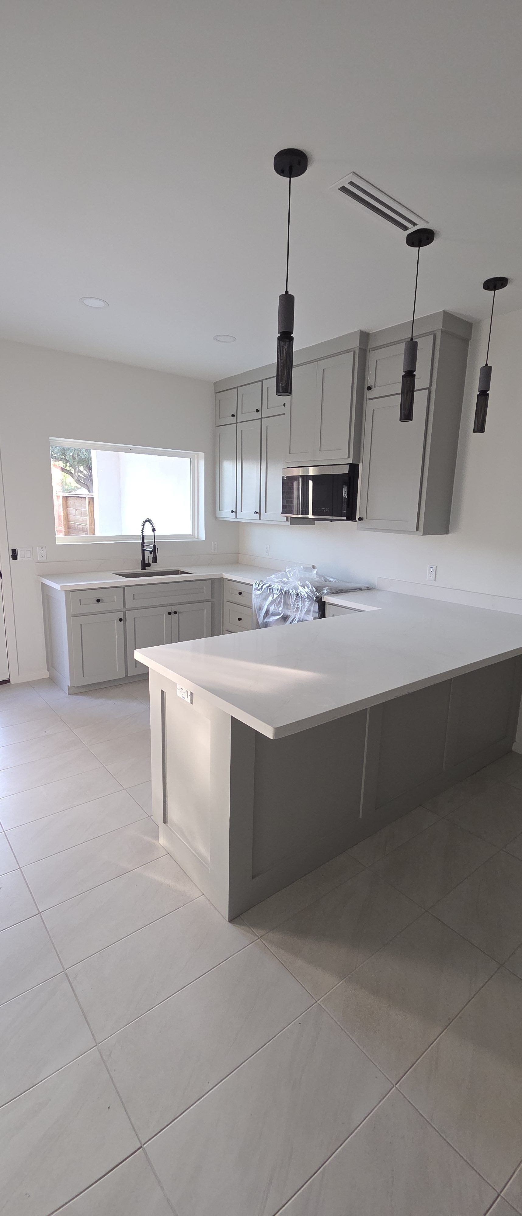 The Houston · kitchen with gray shaker cabinets and three slim pendant lights over the peninsula