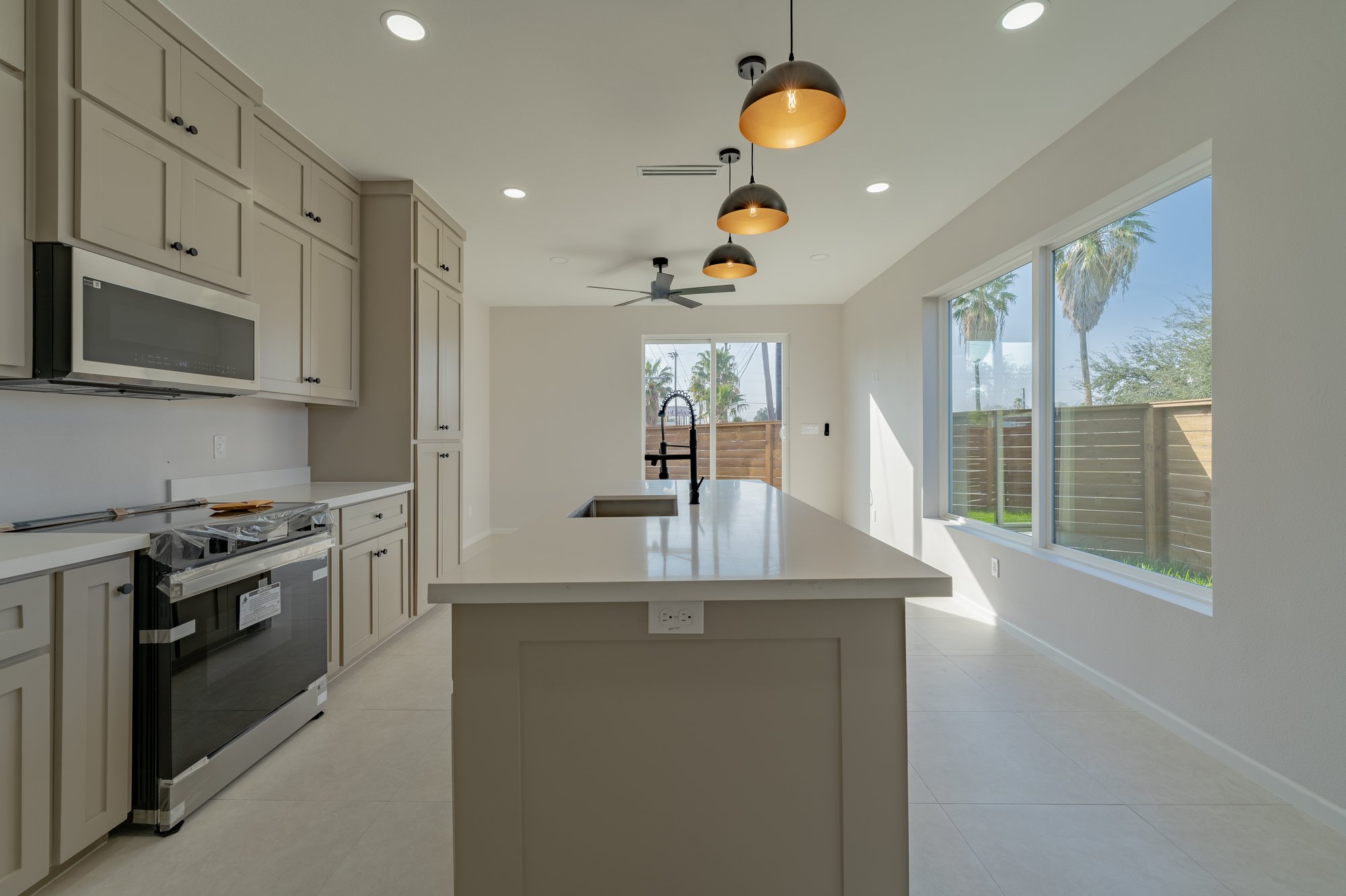 Three Sisters · kitchen island with black faucet and brass pendants