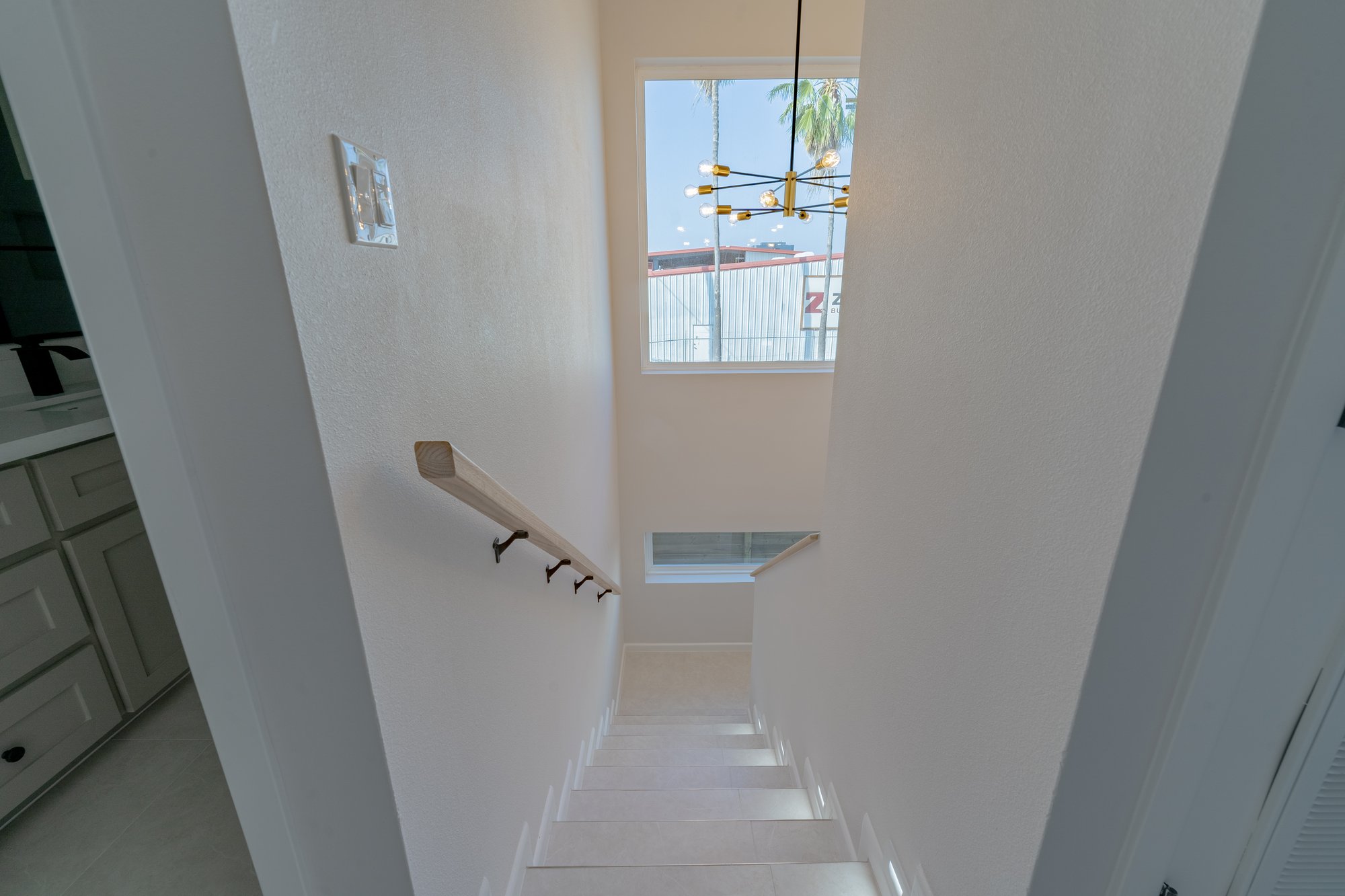 Three Sisters · stair with brass sputnik chandelier and wood handrail