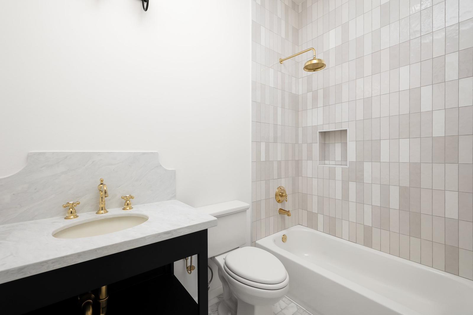 Cassandra Row · guest bath with marble counters and brass shower fixtures