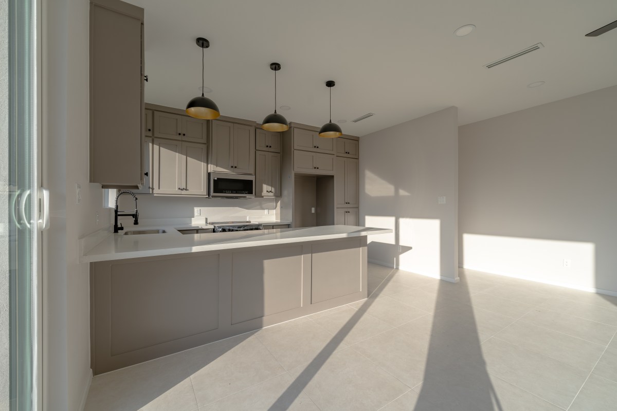 Three Sisters sage shaker kitchen with brass dome pendants
